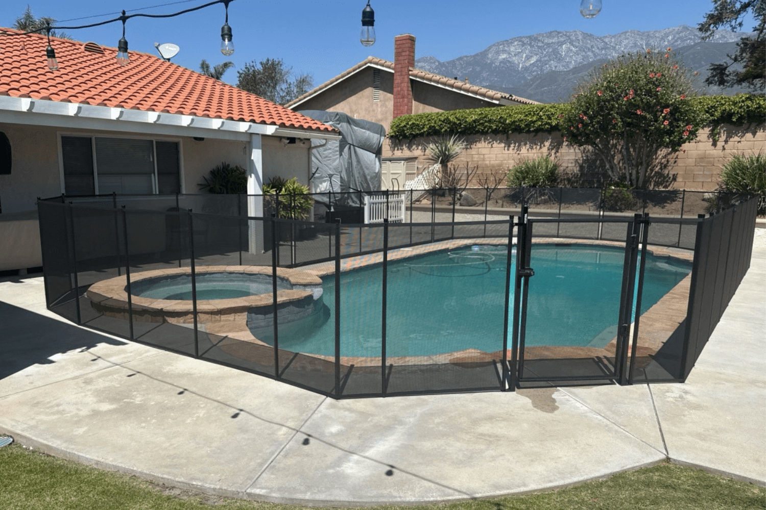 black mesh pool fence installed around a small backyard swimming pool