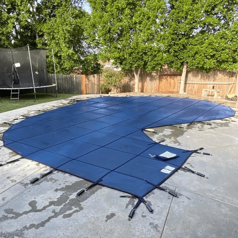 blue mesh pool cover installed over an irregular swimming pool