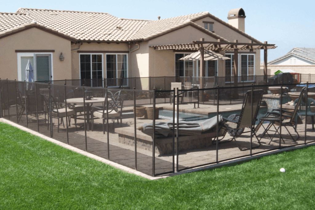 brown mesh removable pool fence installed around a backyard swimming pool
