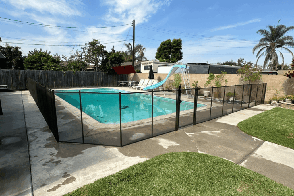 removable mesh pool fence installed around a backyard swimming pool