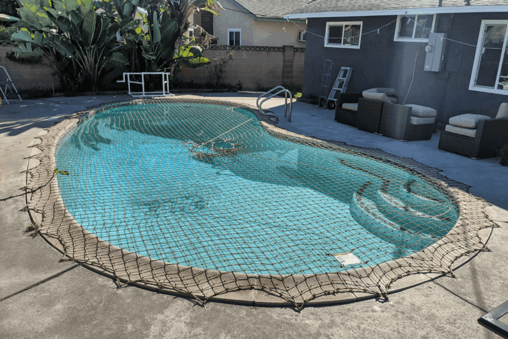 tan pool safety net installed over a backyard swimming pool