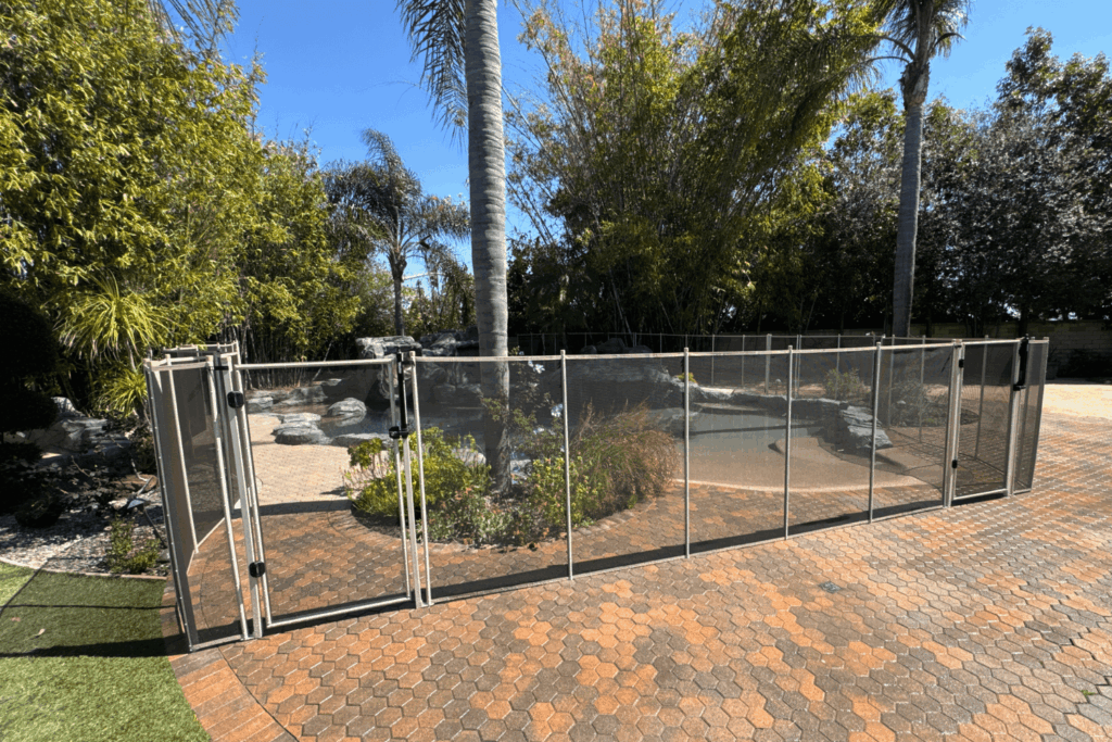 white mesh removable pool fence installed on pavers in a backyard