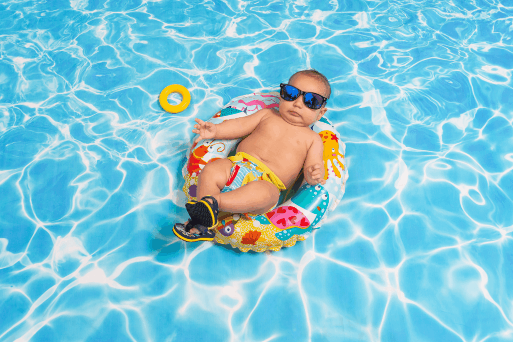 A baby, wearing sunglasses, floating in an inner tube in a pool