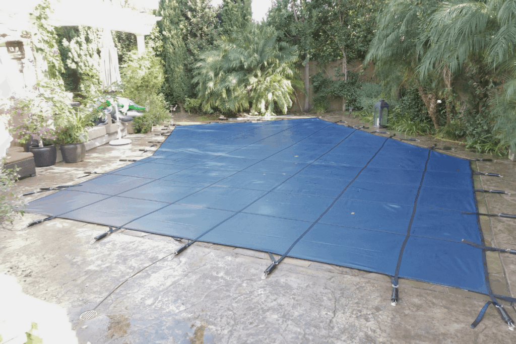 blue mesh swimming pool safety cover installed over a small pool