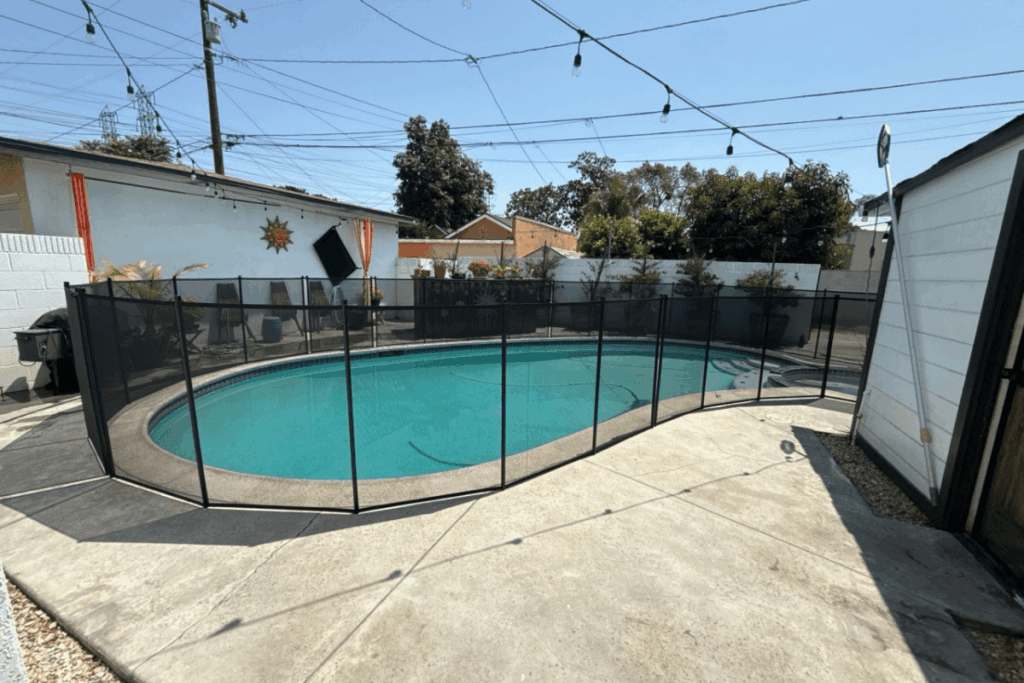 swimming pool with black mesh pool fence surrounding it