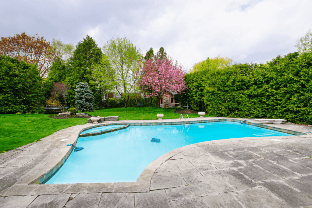 Backyard swimming pool and deck in need of pressure cleaning