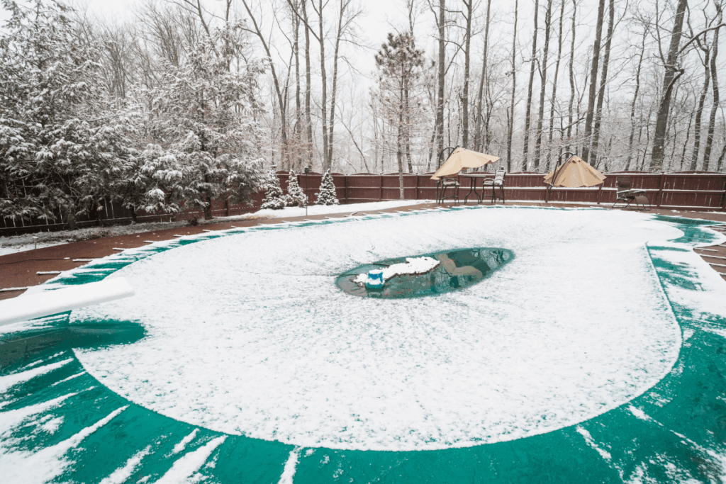 green winter pool cover with snow collecting on top of it