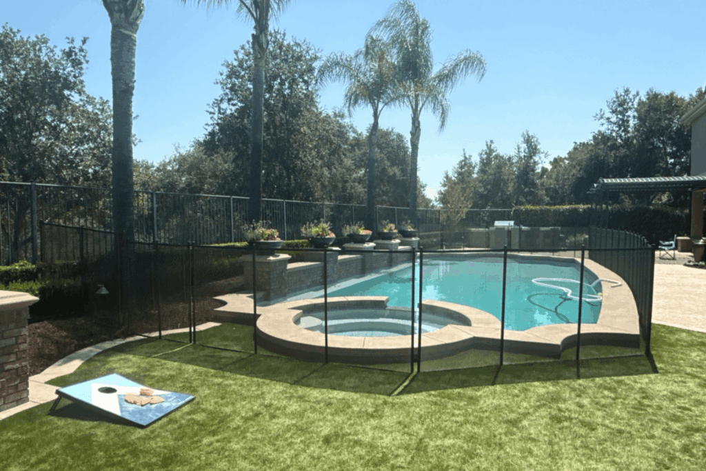 Backyard pool area with a black mesh removable pool fence installed