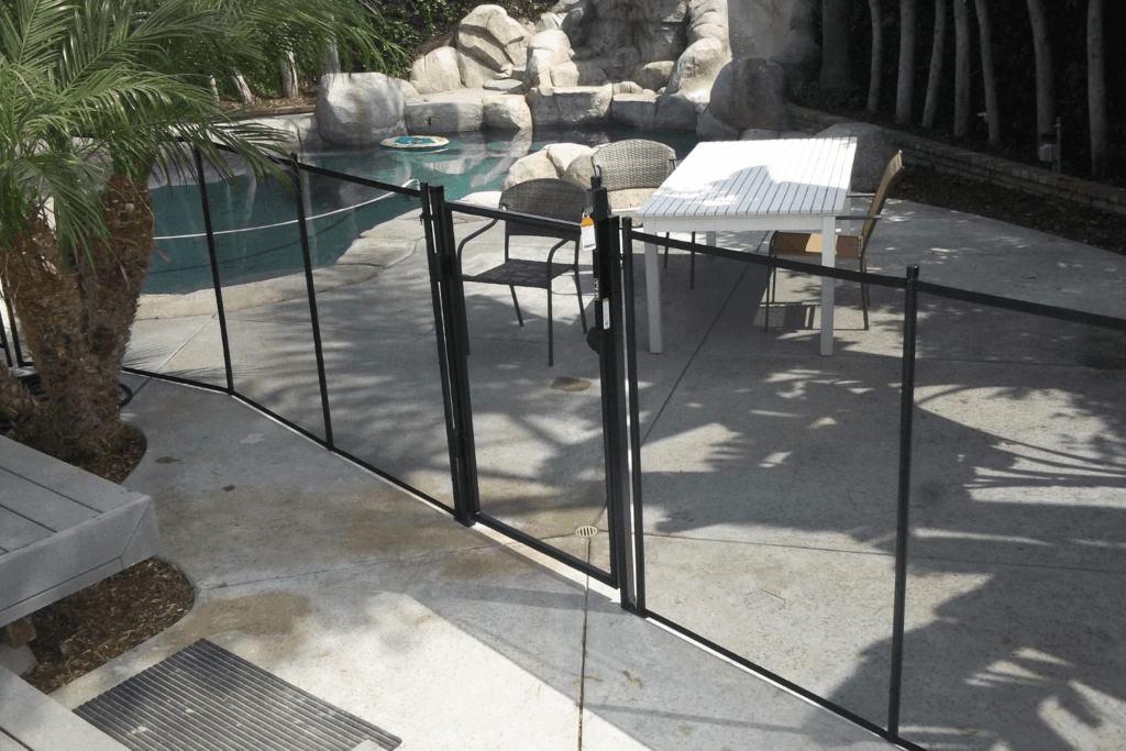 black mesh removable pool fence and gate installed around a swimming pool