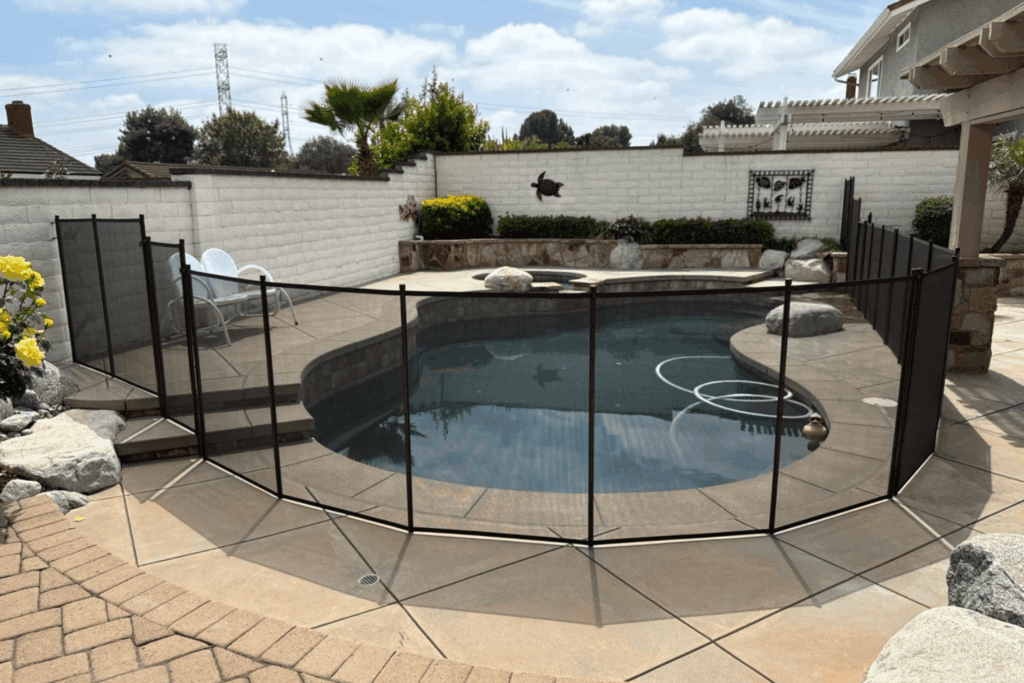 black mesh removable pool fence installed around a swimming pool