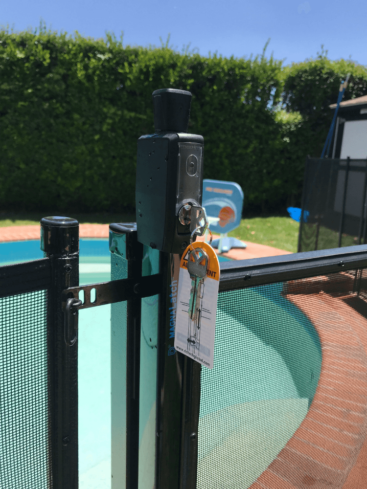 close up of a newly installed mesh removable pool fence with a key inserted into the locking gate