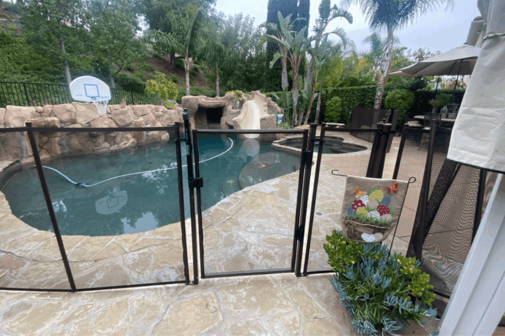 close up view of an installed mesh pool fence with a self closing, self latching gate