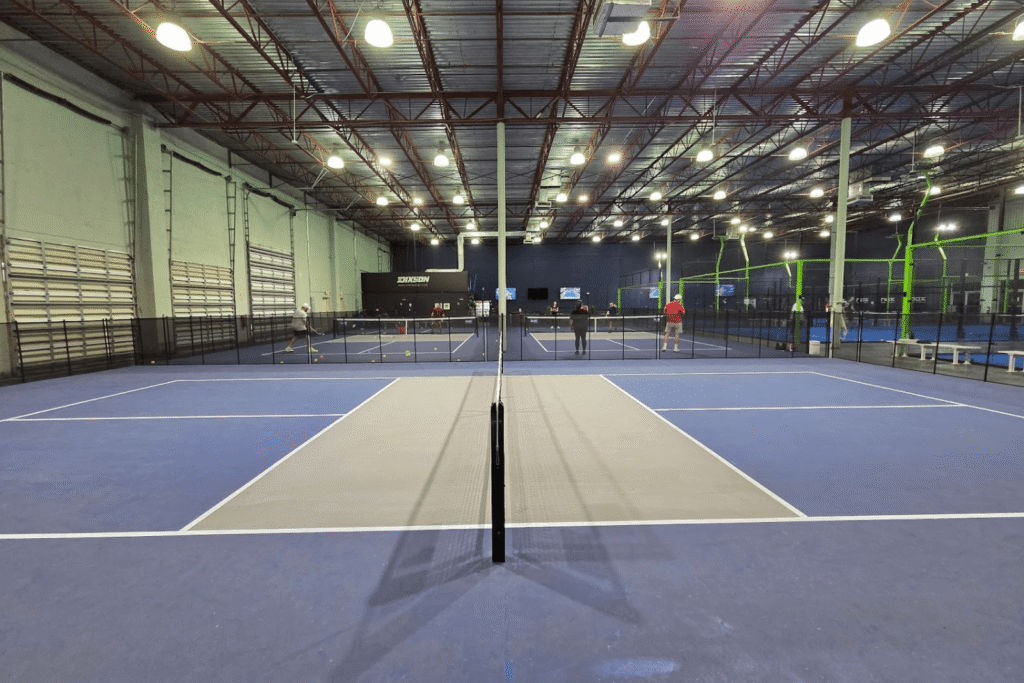 side view of an indoor pickleball court with removable mesh pool fencing installed around it