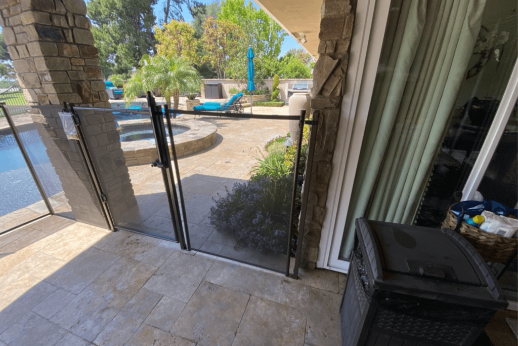 Backyard pool with a black pool safety fence, including its door and latch.