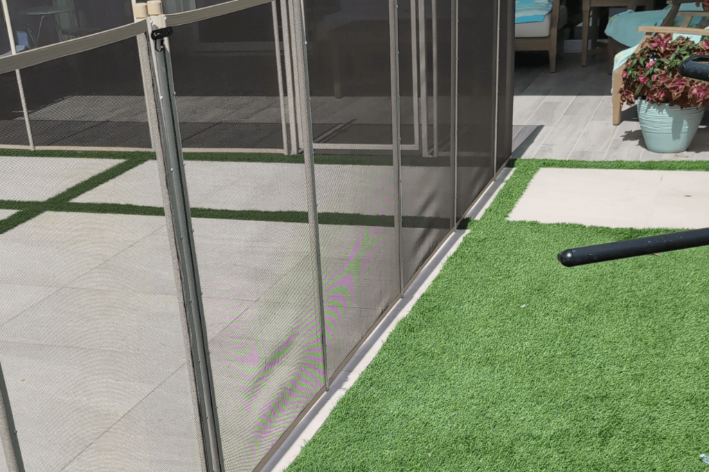 A concrete and turf surface with a mesh safety fence installed on it.