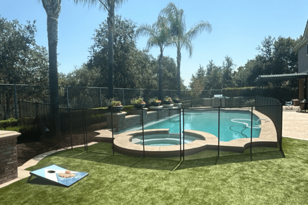 black mesh pool fence installed in grass surrounding swimming pool