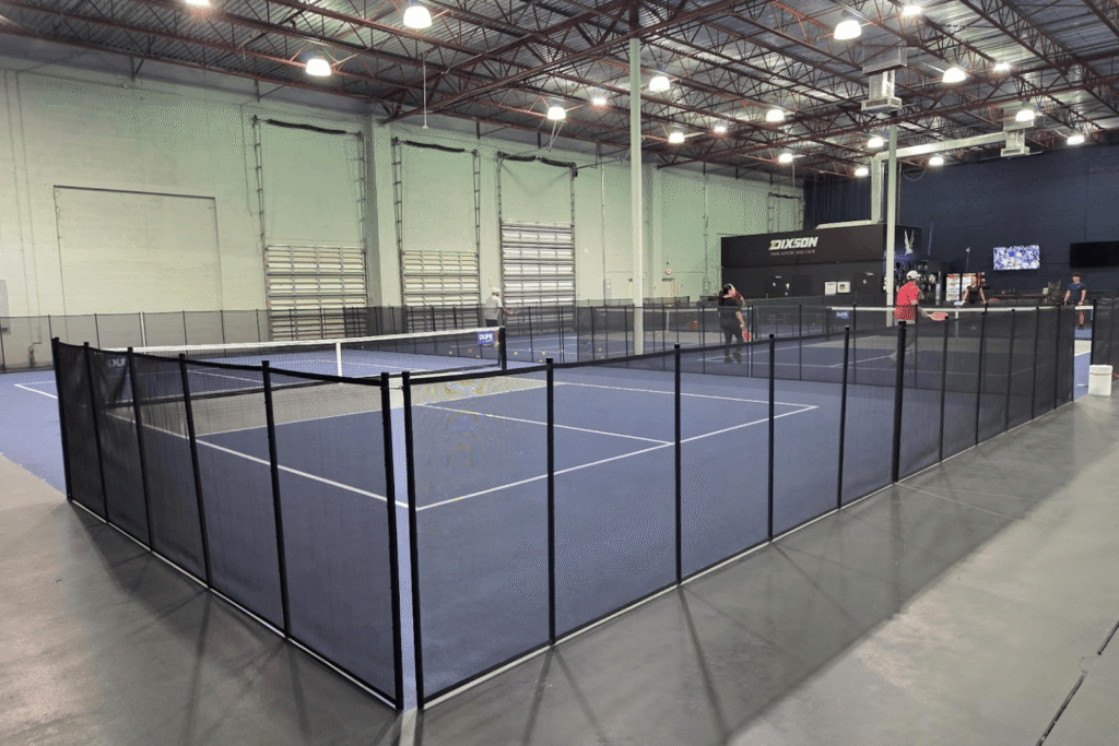 Black mesh removable pool fencing installed surrounding an indoor pickleball court