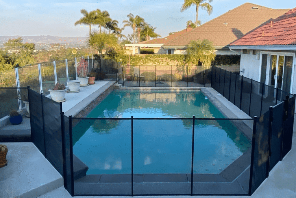 black mesh removable pool fence installed around a hillside backyard pool