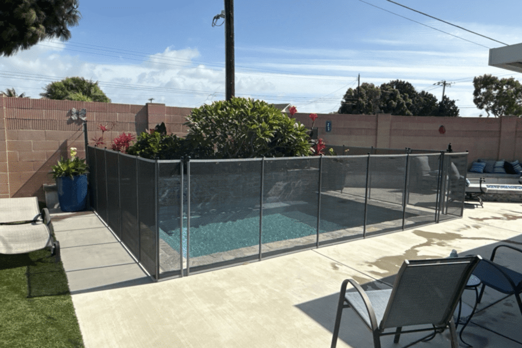 mesh removable pool fence installed around a small backyard swimming pool