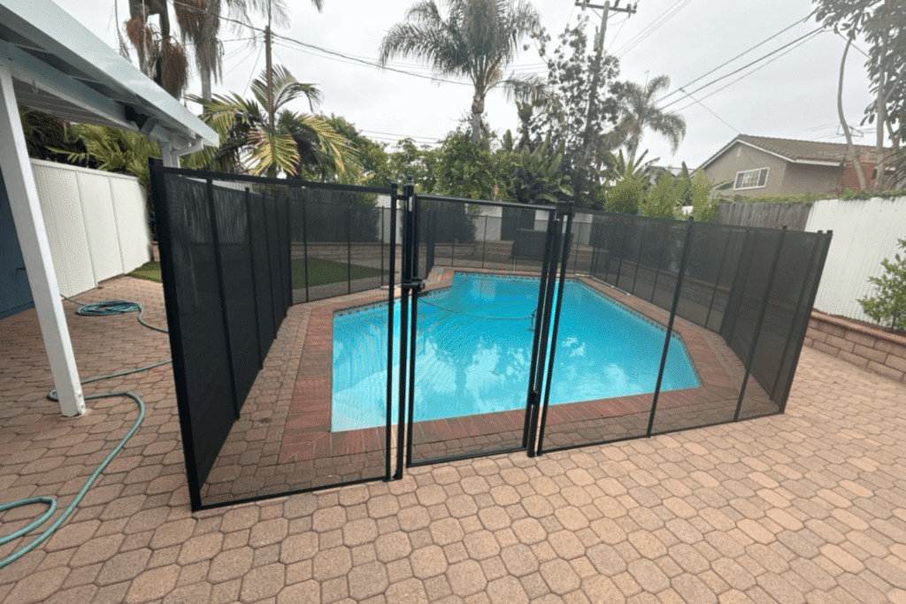 black mesh removable pool fence installed around a small swimming pool