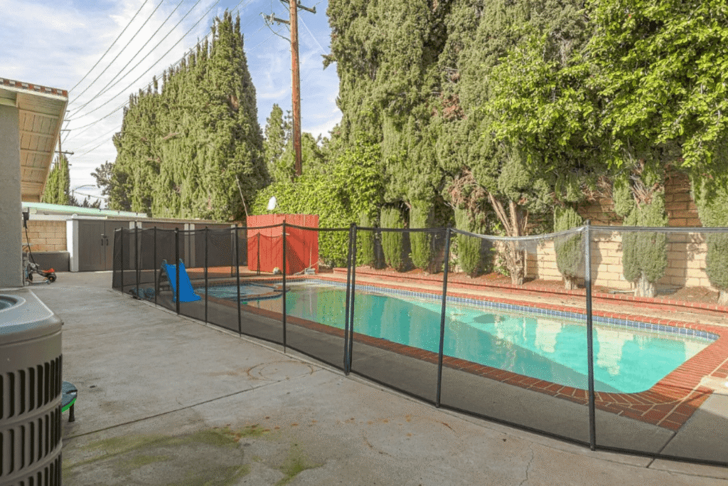 Black mesh pool fence poorly installed by a DIYer