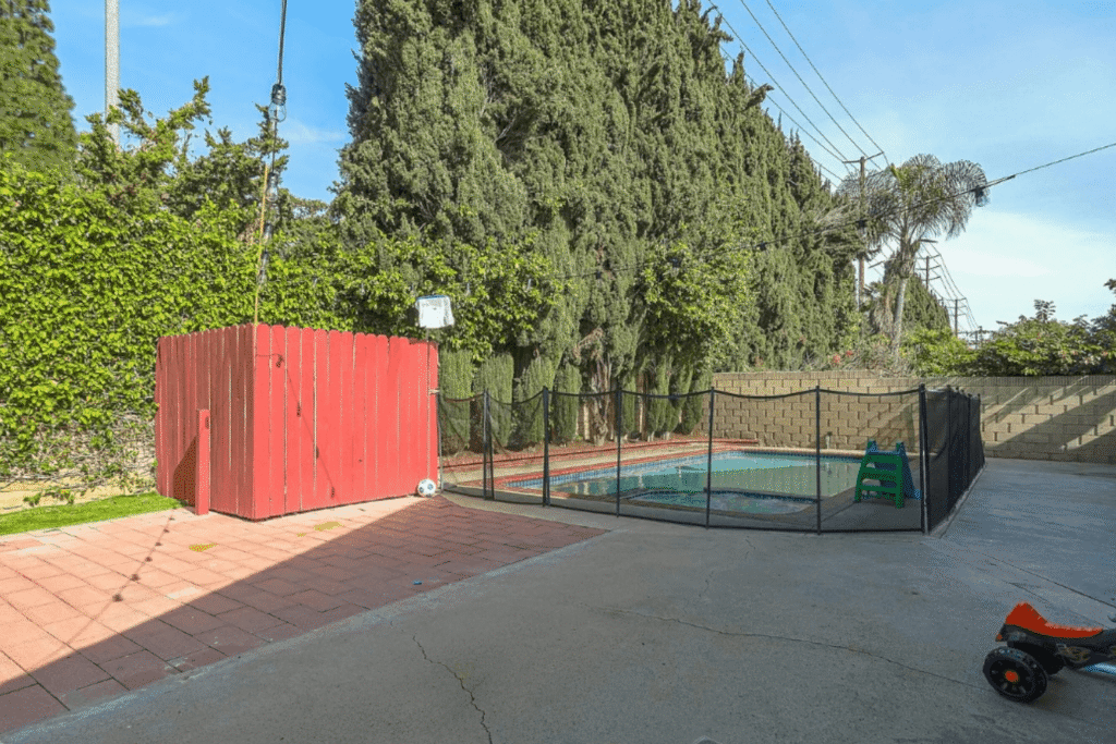 Backyard with a black mesh pool fence installed by a DIYer showing signs of poor installation