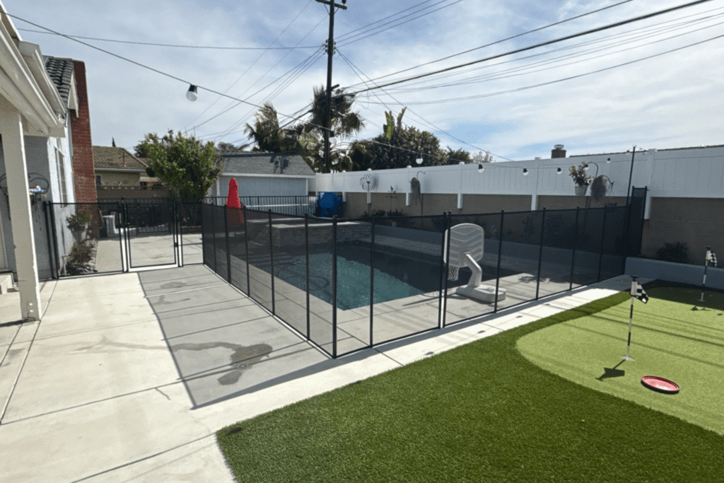 backyard with putting green and swimming pool with black mesh pool fence surrounding it