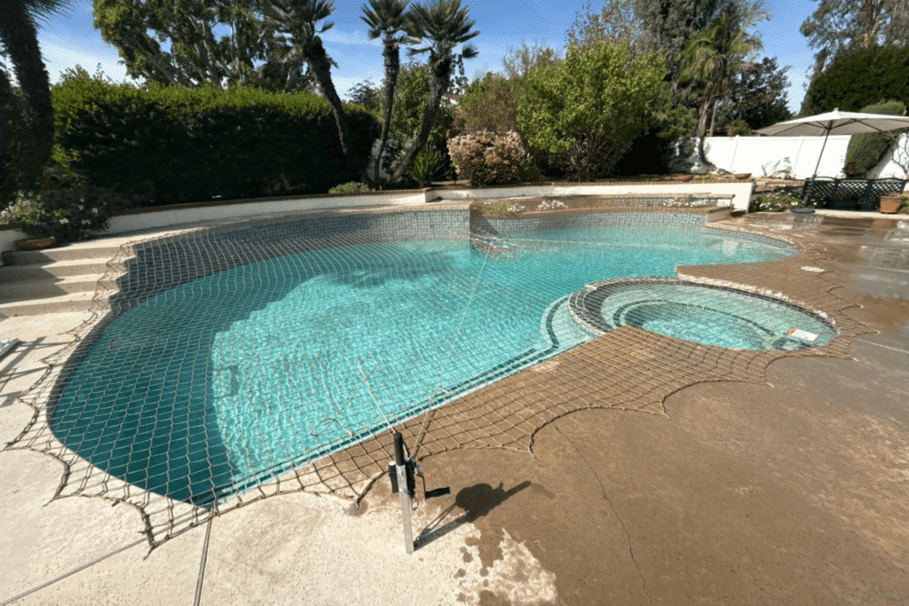 tan pool net installed over a large backyard swimming pool