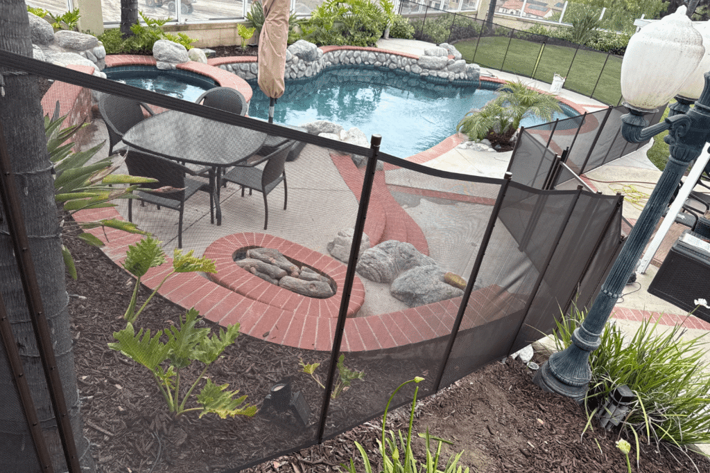 black mesh pool fence installed in a backyard with sloping land