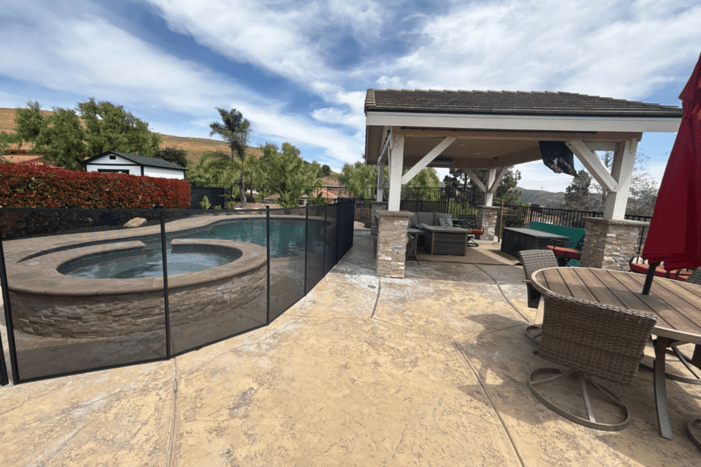 backyard with lounge area and swimming pool enclosed with a black mesh pool fence