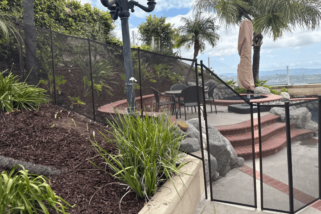 black mesh removable pool fence installed in a sloping backyard with various elevation changes