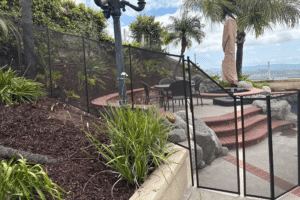 black mesh removable pool fence installed in a sloping backyard with various elevation changes