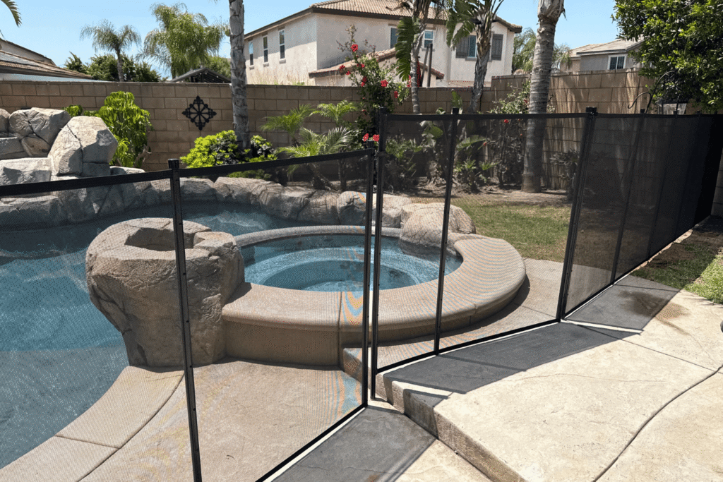 black mesh pool fence installed around a pool with elevation change