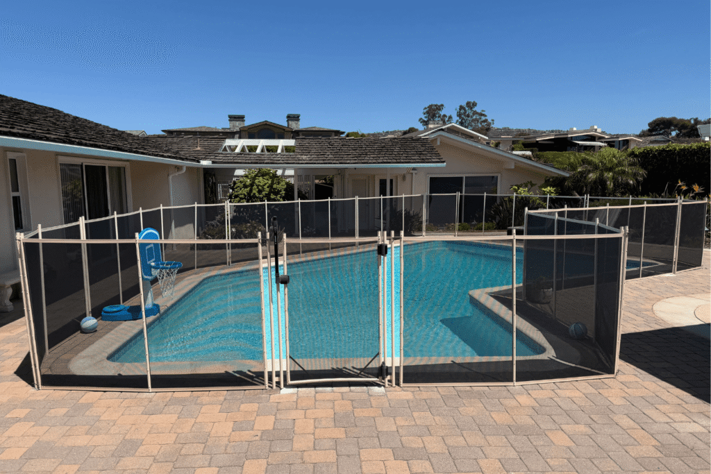 white mesh pool fence surrounding a large backyard swimming pool