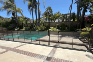 brown mesh pool safety fence bordering a backyard swimming pool