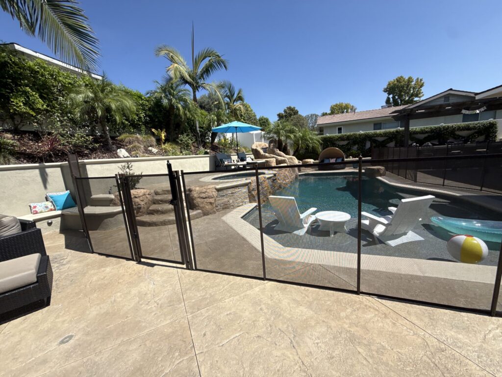 Brown All-Safe removable mesh pool fence with a self-closing gate on a stamped concrete pool deck
