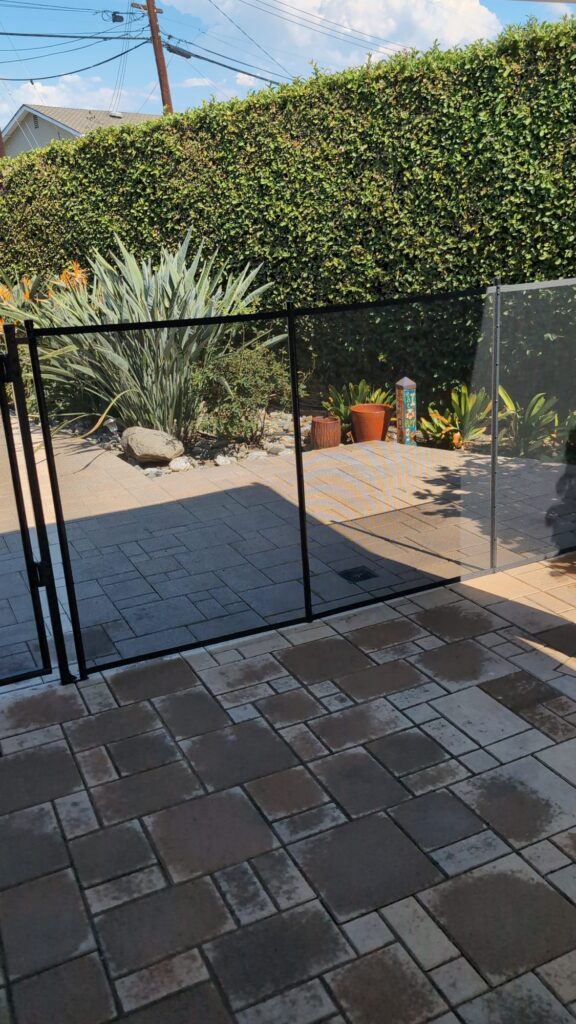 Black mesh pool fence and gate installed on a paver patio