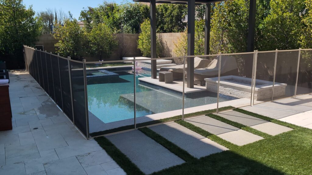 Beige mesh pool fence crossing concrete stepping stones set in artificial turf