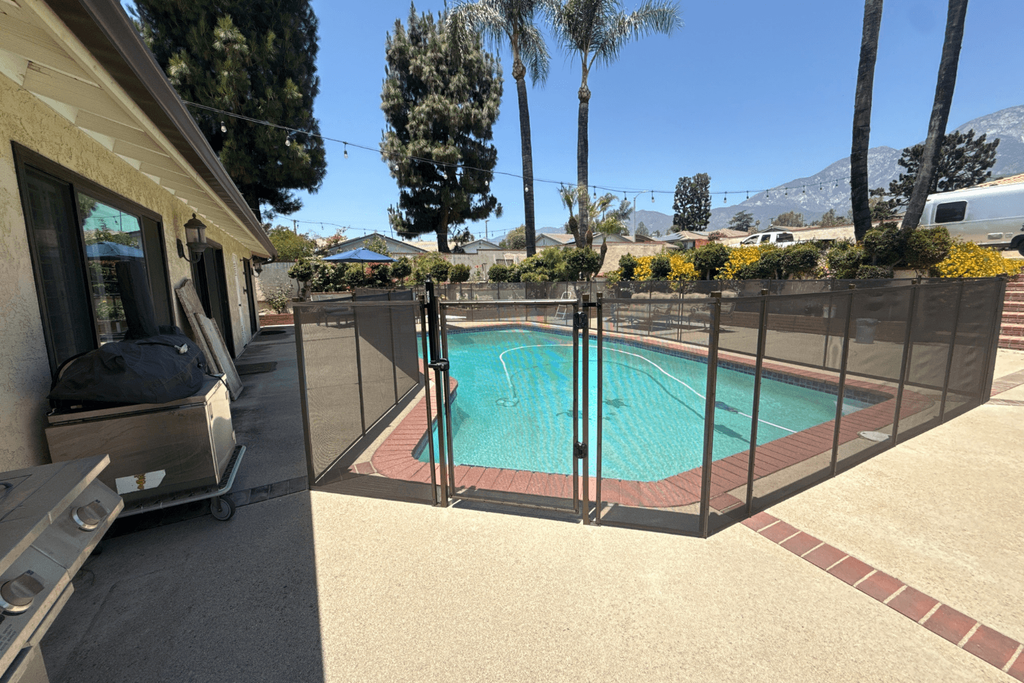 All-Safe black mesh removable pool fence installed surrounding a backyard swimming pool