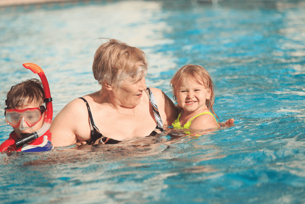 Grandmother in the swimming pool with her young grandson and granddaughter