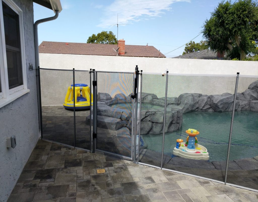 white mesh pool fence with baby toys behind it