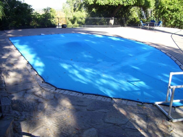 Blue leaf cover over a freeform pool on a flagstone deck