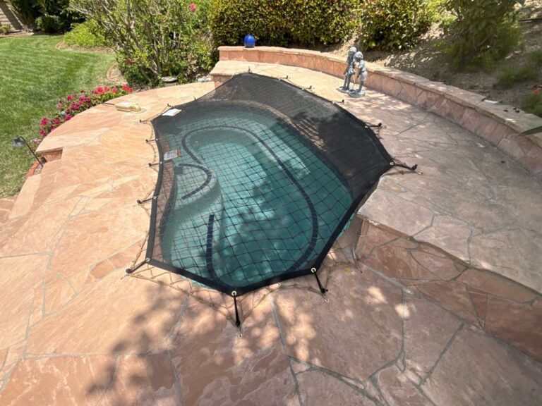 Black leaf cover over a pool and raised spa with an ocean view