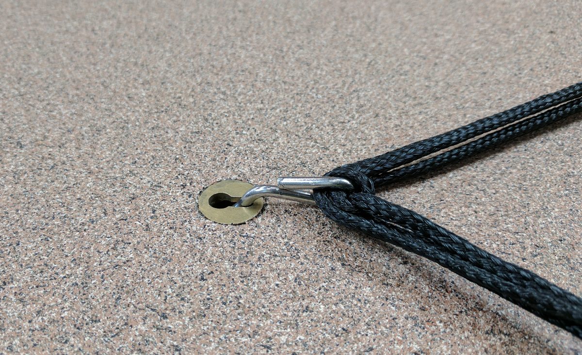 Brass keyhole anchor set in a pool deck with a clip attached