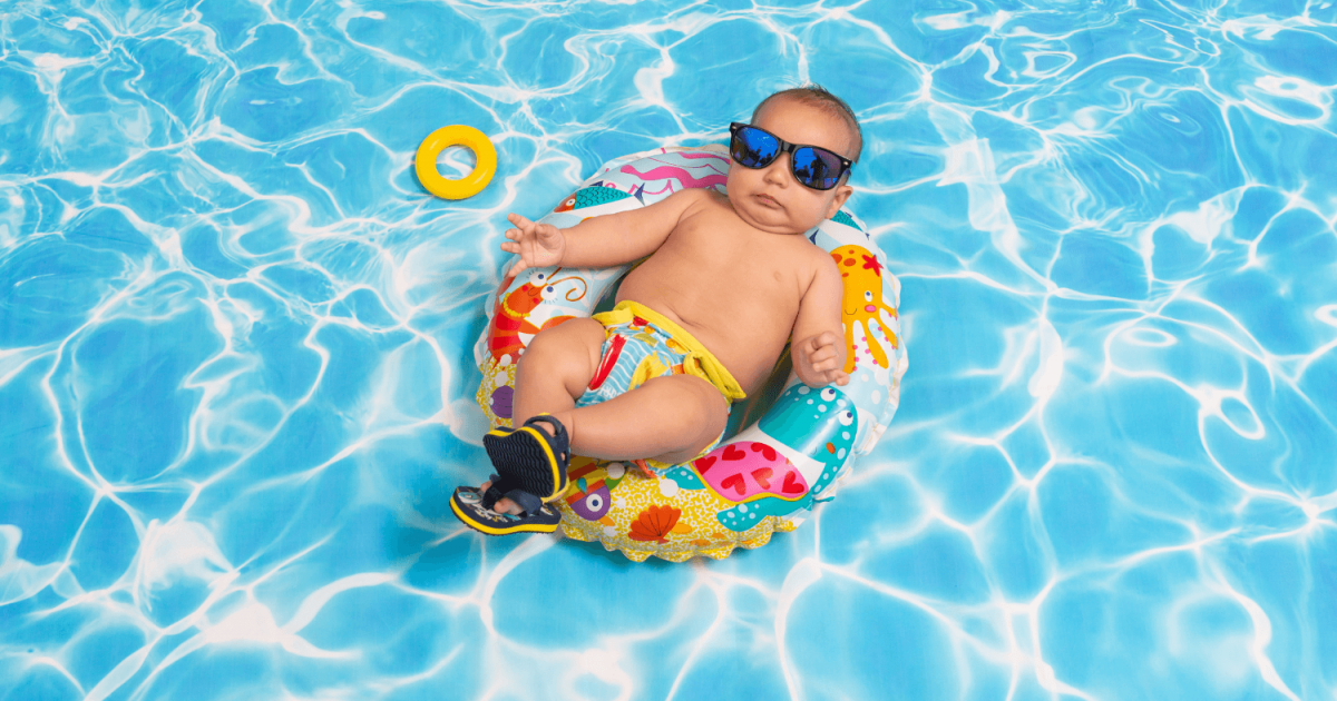 A baby, wearing sunglasses, floating in an inner tube in a pool