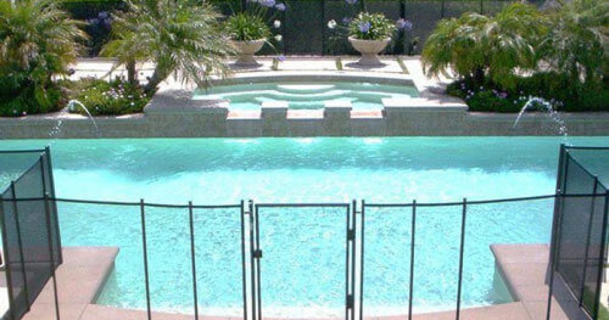 backyard swimming pool with a black mesh pool fence surrounding it