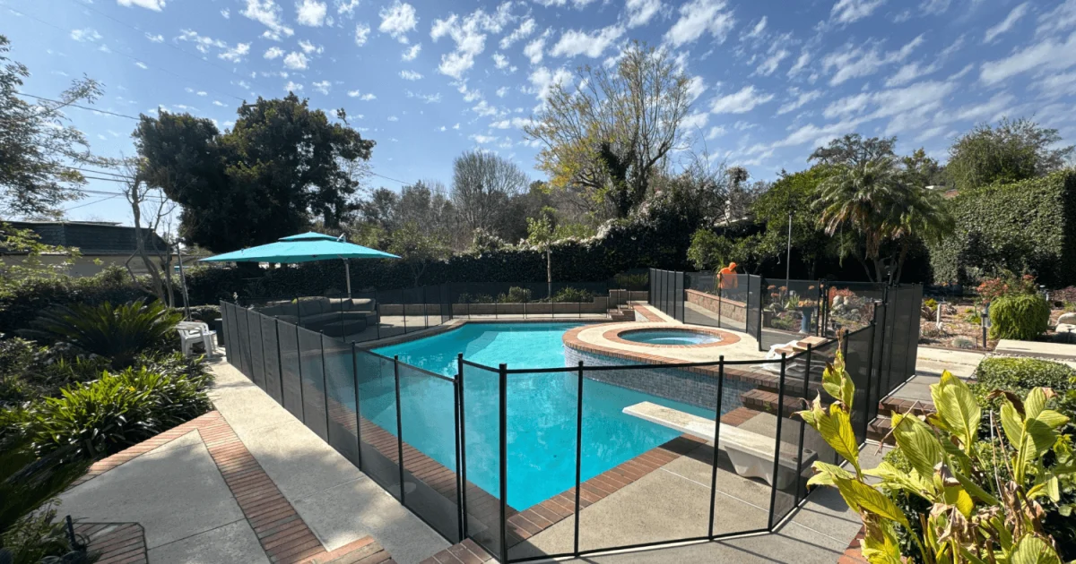 Black mesh removable pool fence installed around a backyard swimming pool