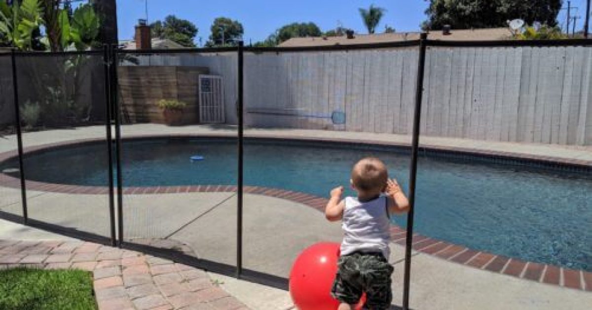 Child looking through Mesh Pool Fence with Beach Ball