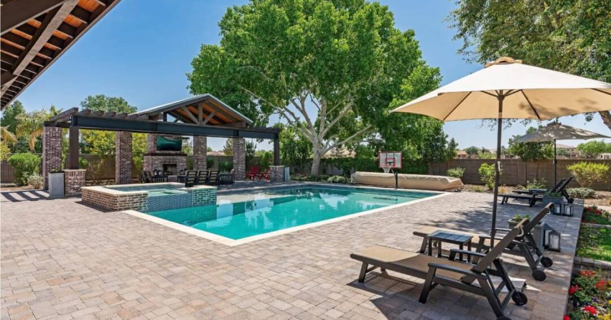 Beautiful residential backyard showing a large swimming pool and a brick pool deck
