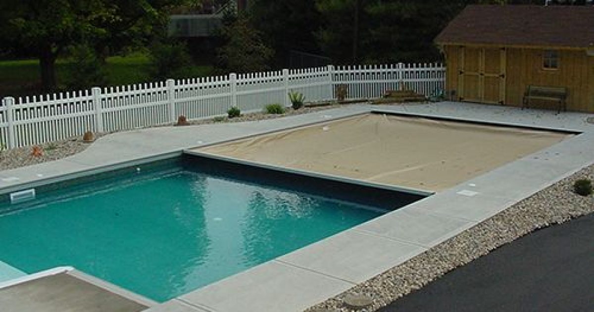 tan automatic pool cover half extended over a pool